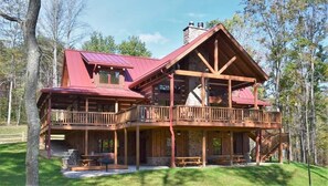 A large, multi-level wooden cabin with a red roof, multiple balconies, and a stone chimney. - Wildcat Lodge - Luxury Accommodations (Rockbridge)