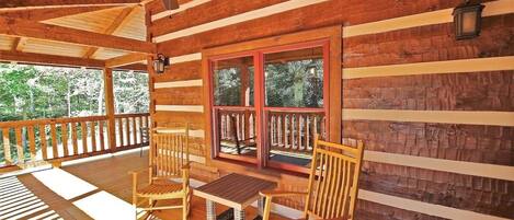 A wooden cabin with a porch, a ceiling fan, and a table with chairs.