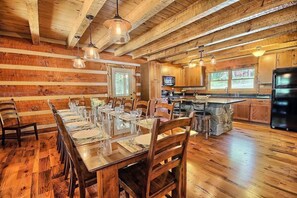 Ein rustikales Holzinterieur mit Essbereich, Küche und Kamin aus Stein.