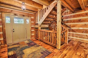 Ein Holzinnenraum mit Treppe, einer Tür mit Fenstern und einem gemusterten Teppich.