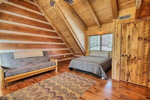 A cozy attic bedroom with a wooden sloped ceiling, a sofa, a bed, and a wardrobe. - Wildcat Lodge - Luxury Accommodations (Rockbridge)