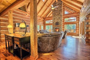 Ein Holzblockhaus-Interieur mit Kamin, Ledersitzgelegenheiten und einem Holztisch mit Lampen.
