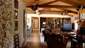 A cozy living room with a fireplace, wooden ceiling beams, and a bookshelf filled with books and decorative items. - Enjoy the RANCHO Villa Heart of Temecula Wine Country Golf Casinos Views RVC-023 (Temecula)