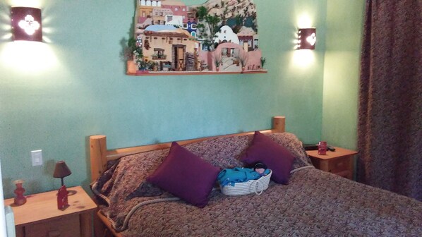 A bedroom with a bed, purple pillows, a basket of clothes, and two bedside tables with lamps. - Art, hiking, relaxing under the stars in Julian/Anza Borrego
(Julian)