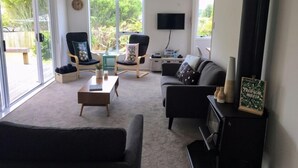 Un salon moderne comprenant un canapé, deux fauteuils, une table basse, un téléviseur et une cheminée.