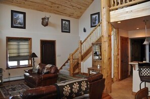Cozy living area with a high ceiling, wooden beams, and a leather sofa.