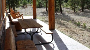 Eine Holzterrasse mit Picknicktischen und Bänken, mit Blick auf ein bewaldetes Gebiet.