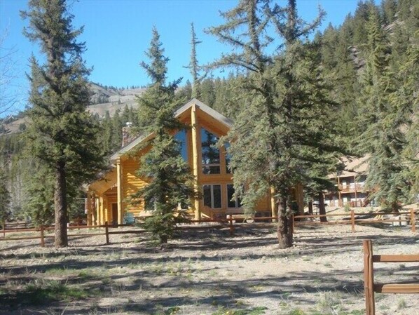 Surrounded by a forest, this cabin features a gabled roof and large windows, blending seamlessly into its natural surroundings.
