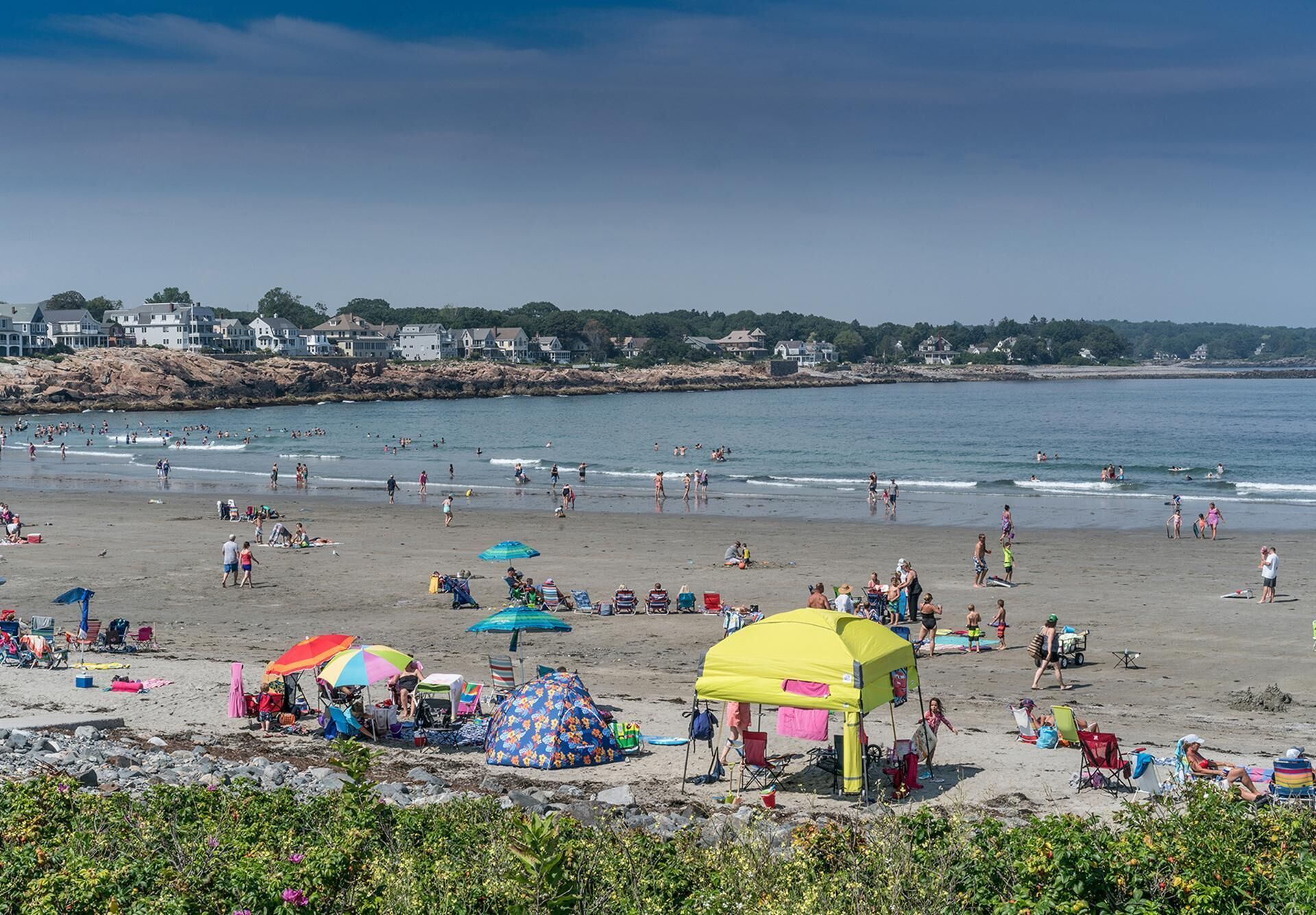 A beach with people, umbrellas, and tents.