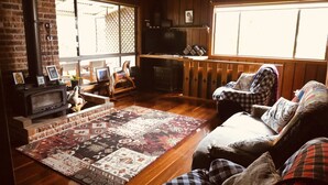 Ein gemütliches Wohnzimmer mit Kamin, Holzmöbeln und einem großen Fenster.