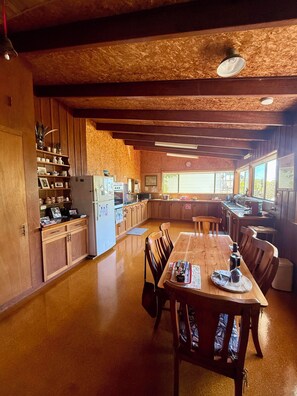 Eine geräumige Küche mit Holzausbau, einem Esstisch mit Stühlen und einem großen Fenster für natürliches Licht.