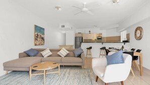 A modern living room with a sofa, coffee table, and dining area.