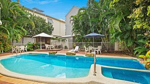 Relax in a serene pool area surrounded by lush tropical vegetation and comfortable lounge seating.