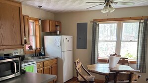 A kitchen with wooden cabinets, a refrigerator, a microwave, a dining table with chairs, and a ceiling fan. - Rickett's Glen state Park!  Our cabin is only 1/2mile from the trail head. (Benton)