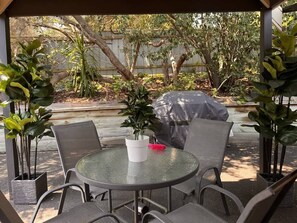 An outdoor patio with a round table, chairs, and potted plants.