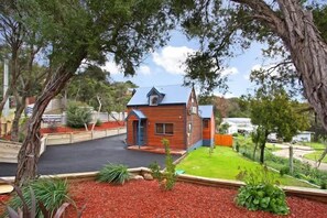 A small wooden house with a sloped roof, surrounded by a landscaped garden with red mulch and green plants. - Ocean Breeze Retreat - indoor pool, spa and sauna (Tootgarook)