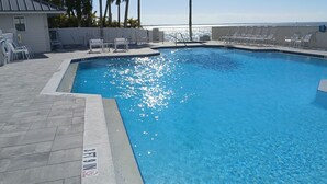 A swimming pool with clear blue water, surrounded by lounge chairs and a view of the ocean. - Sanibel Harbour Resort - Panoramic Beachfront Luxury 2/2 Condo! (Fort Myers)