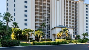 A multi-story hotel with balconies, palm trees, and a well-maintained lawn. - Sanibel Harbour Resort - Panoramic Beachfront Luxury 2/2 Condo! (Fort Myers)