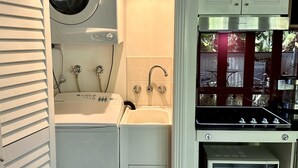 Eine kompakte Küche mit integrierter Waschmaschine und Trockner, einem Spülbecken und einer Mikrowelle.