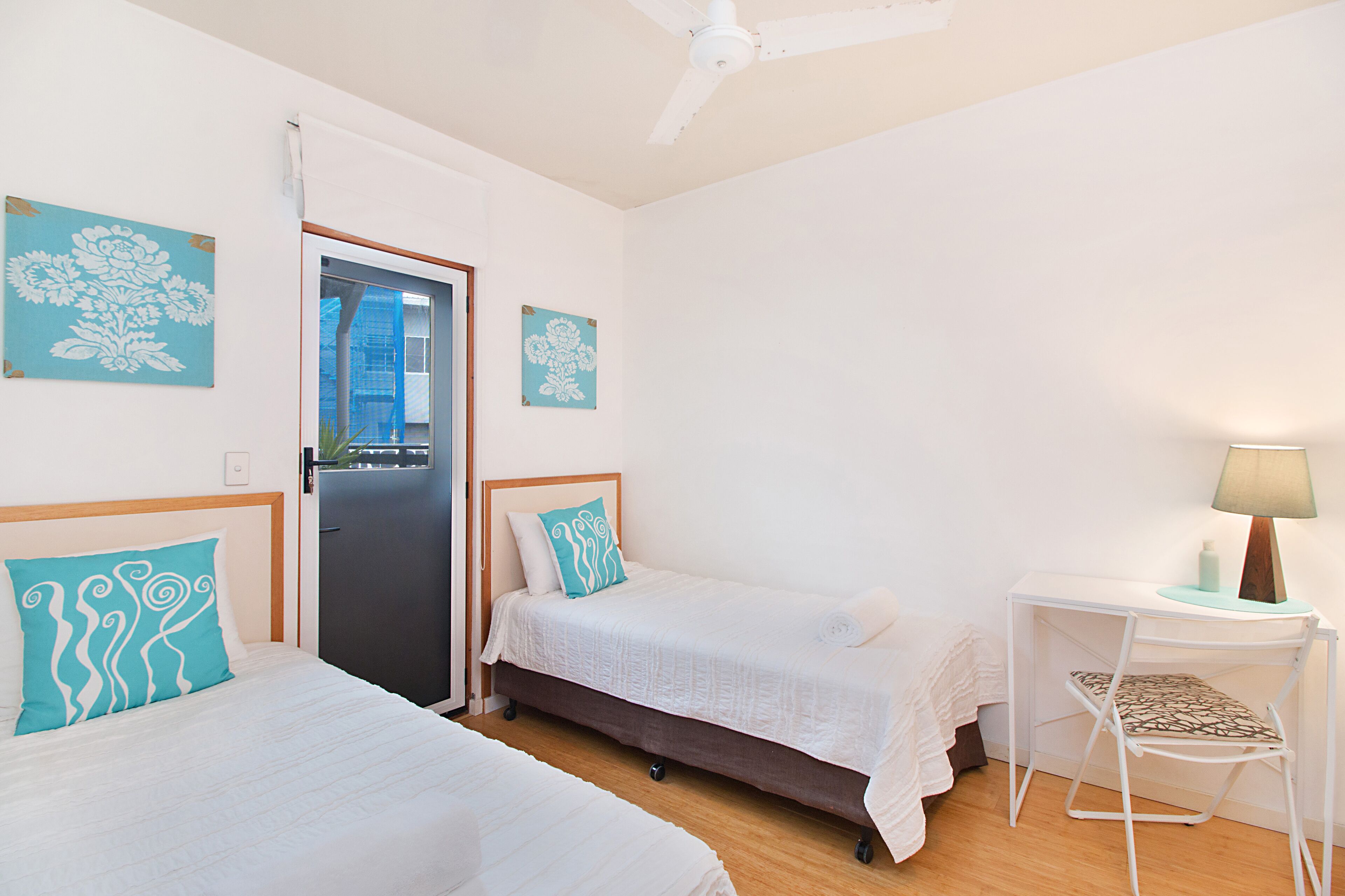 A bedroom with two beds, a desk, and a chair.