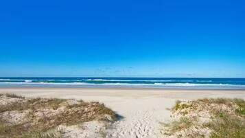 A beach with a clear sky and waves in the background.