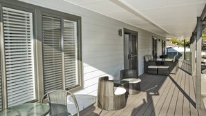 En inglasad veranda med möbler av rotting, ett bord och en dörr som leder in till huset.