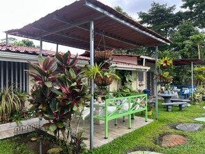 A covered outdoor area with a patio, hanging plants, and outdoor furniture.