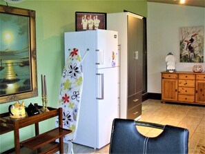 Une cuisine équipée d’un réfrigérateur, d’un meuble en bois et d’une table à manger avec une chaise.