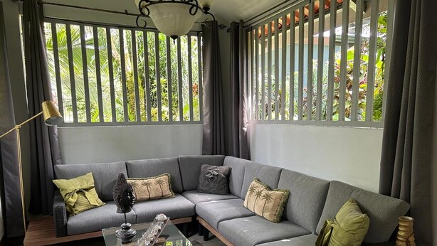 A modern living room with a grey sectional sofa, a glass coffee table, and a wicker side table. - Rent 1 apt for up to 6 guests  both apt for up to 12 guests and a discount (Guapiles)