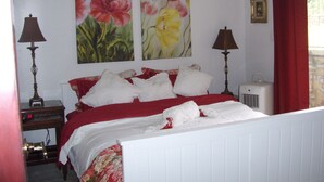 Een slaapkamer met een bed, twee wandlampen, een radiator en twee bloemschilderijen.