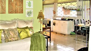A room with a sofa, a dining table with chairs, a kitchen area, and a ceiling fan. - Rent 1 apt for up to 6 guests  both apt for up to 12 guests and a discount (Guapiles)