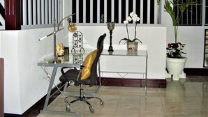 A modern office space with a desk, chair, and decorative items including a lamp, a vase with flowers, and a potted plant. - Rent 1 apt for up to 6 guests  both apt for up to 12 guests and a discount (Guapiles)