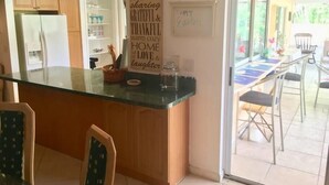 Una cocina con isla de vidrio, armarios de madera y un comedor con mesa y sillas.
