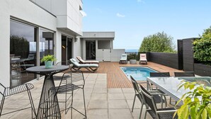 A modern outdoor patio with a pool, lounge chairs, and a dining area. - Azure - Absolute Beachfront Luxury, Wifi, Spa (Lorne)