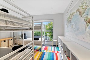 A modern child’s room with bunk beds, a colorful rug, a small table, and a world map on the wall. - Azure - Absolute Beachfront Luxury, Wifi, Spa (Lorne)