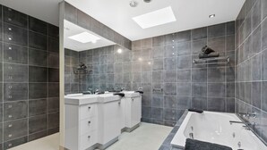 A modern bathroom with two sinks, a bathtub, and a large mirror. - Azure - Absolute Beachfront Luxury, Wifi, Spa (Lorne)