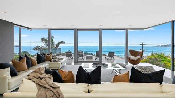 A modern living room with a large glass wall overlooking the sea, furnished with sofas and chairs, and a coffee table. - Azure - Absolute Beachfront Luxury, Wifi, Spa (Lorne)