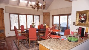 A dining area with a wooden table, red chairs, and a chandelier. - Large 6 Bedroom Home- Ski-in / Ski-out Access (202983-2164) (Snowmass Village)