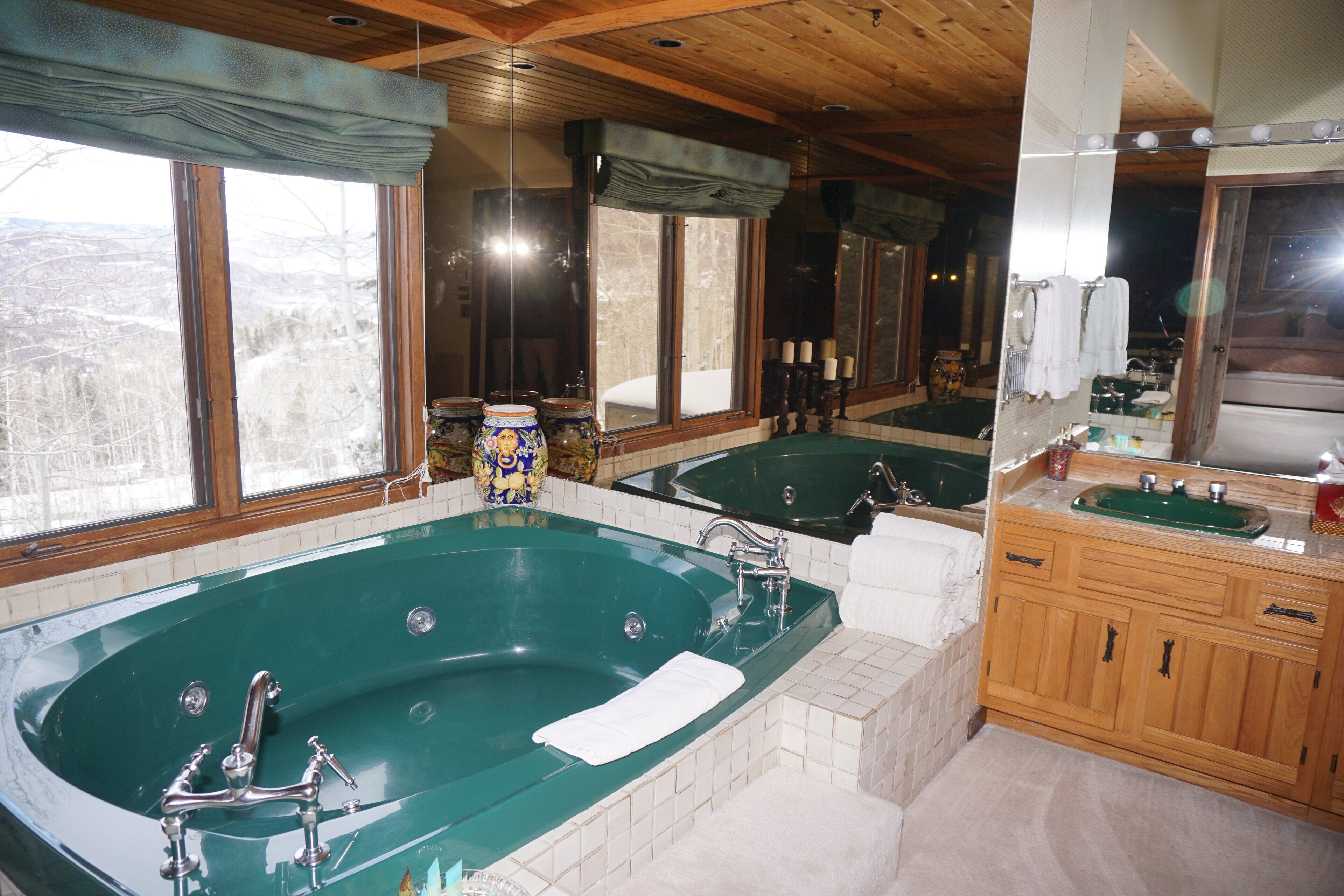 A large bathroom with two separate tubs, wooden cabinets, and a large mirror.