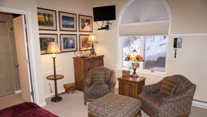 A cozy room with two armchairs, a wooden cabinet, a lamp, and a television on the wall. - Large 6 Bedroom Home- Ski-in / Ski-out Access (202983-2164) (Snowmass Village)