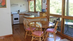 Een keuken met een fornuis, gootsteen en een houten eettafel met stoelen.