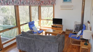 Een gezellige woonkamer met een bank, stoelen, een televisie, een tafel en een open haard.