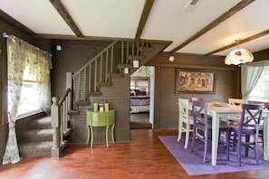 Step into a charming room with a unique wooden staircase, dining area, and cozy seating.