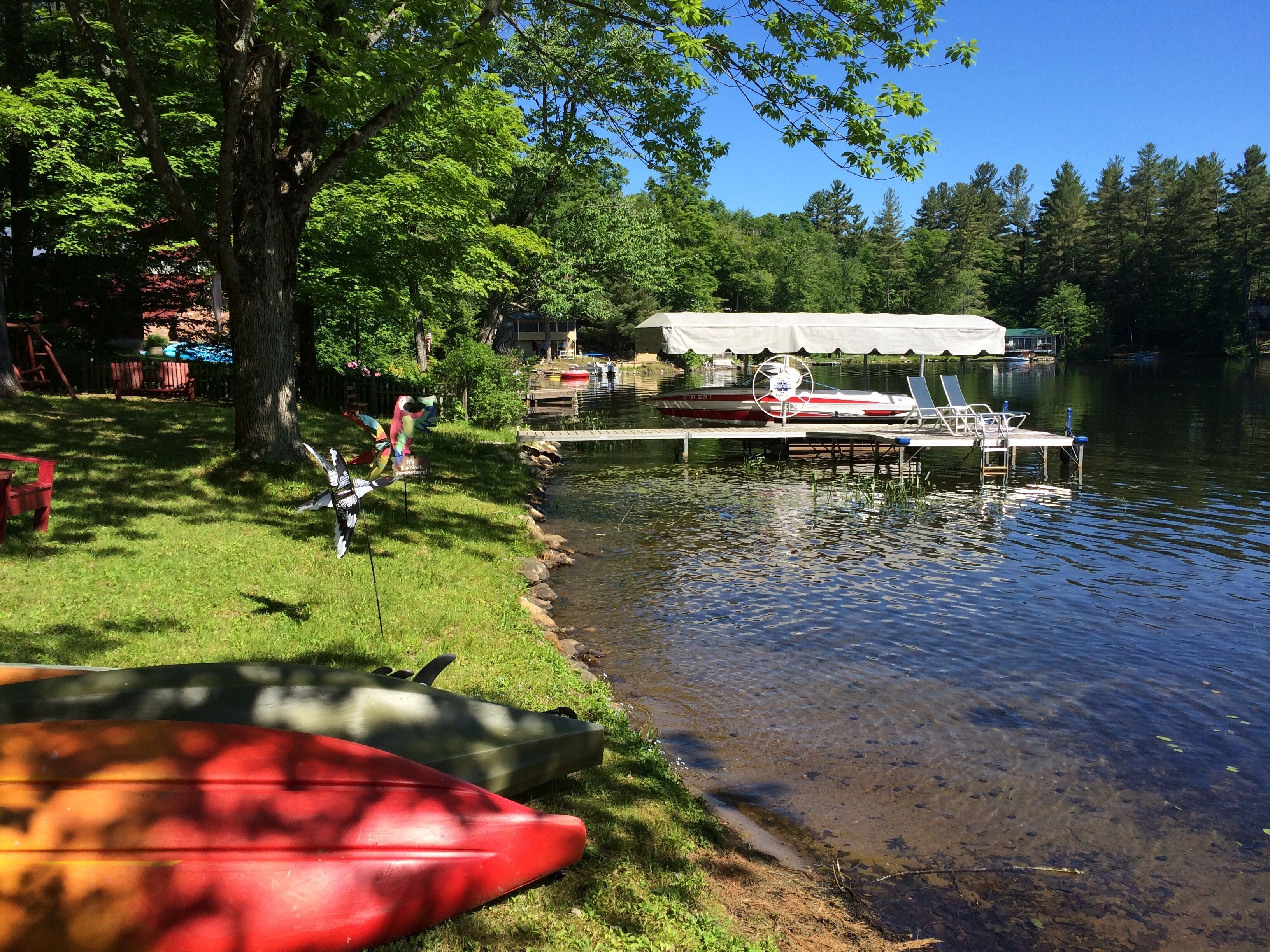 A lakeside setting with canoes, a dock, and a covered area.