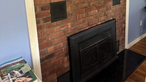 A brick fireplace with a black surround, a framed picture on the wall, and a magazine on a table. - Lake Rescue Vacation Home- Pets Welcome-Okemo and Killington close!!! (Ludlow)