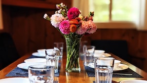 A dining table set with plates, glasses, and a vase of flowers. - Amenities & Resort Access Included, Cabin 4 (Phelps)
