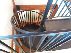 Staircase leads to an upper floor with a wooden handrail and metal balustrade.