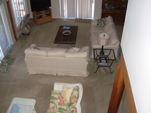 Relax in this inviting living room with a sofa, coffee table, and side table, featuring a mounted television and a window with blinds.