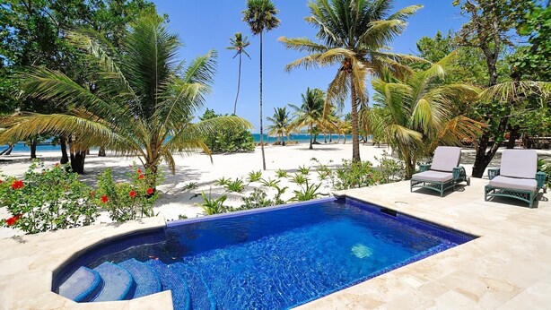 A swimming pool with a view of the beach and palm trees. - Beachfront | Beachside Private Pool | Immaculately Kept | Private Dive Resort (Roatan)