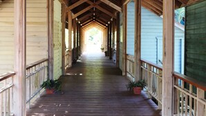 A covered wooden walkway with railings and potted plants. - Beachfront | Beachside Private Pool | Immaculately Kept | Private Dive Resort (Roatan)